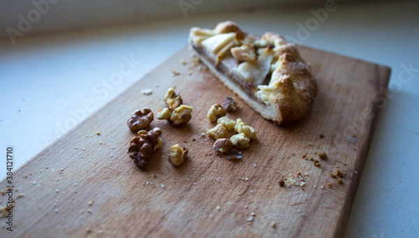 Fototapeta a piece of pie with pear and nuts on a wooden plank