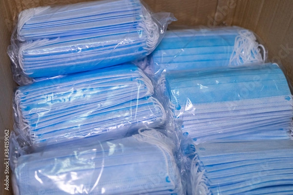 Obraz Medical surgical face mask inside boxes on wooden background. View from above