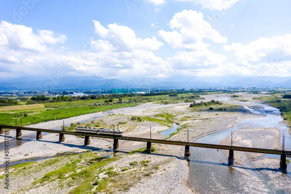 Fototapeta 北アルプスを背景に常願寺川を渡る富山地方鉄道本線の普通列車