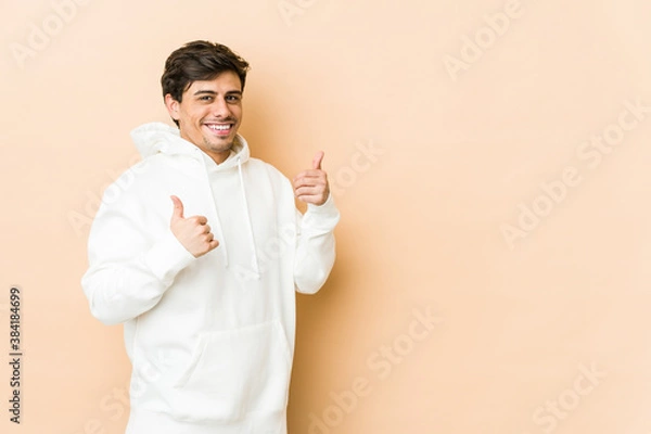 Fototapeta Young cool man raising both thumbs up, smiling and confident.
