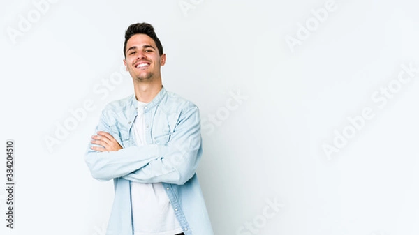 Fototapeta Young caucasian man isolated on white background who feels confident, crossing arms with determination.