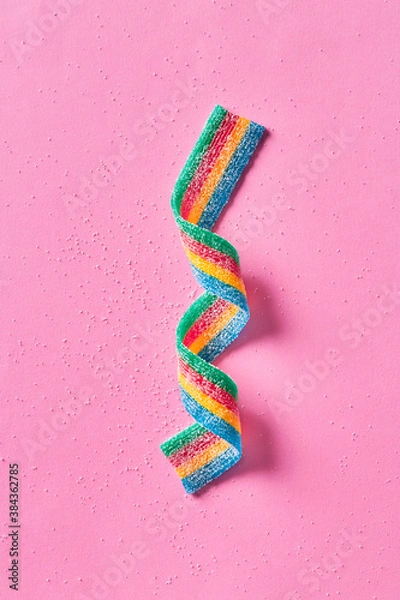 Fototapeta Colorful sugar candy ribbon on a pink background viewed from above. Top view. 