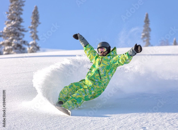 Obraz male snowboarder curved and brakes spraying loose deep snow on the freeride slope. downhill with snowboards in fresh snow. freeride world champion. swirls of snow in the air, in a bright mask