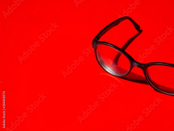 Obraz black framed spectacles close up on red background