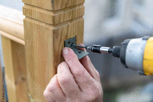 Fototapeta close up of carpenter hands building home decking railing, home improvments