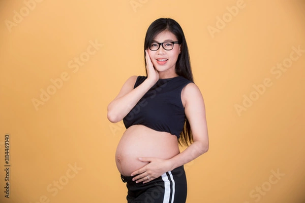 Fototapeta Happy pregnant woman on a yellow background, maternity readiness