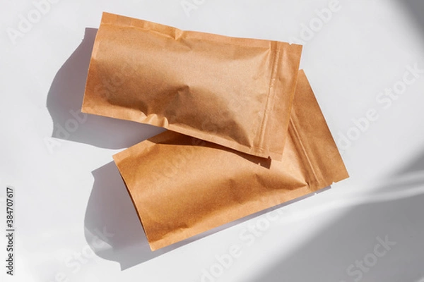 Fototapeta Brown kraft paper pouch bags with coffee beans top view with shadow isolated on white background. Packaging for foods and goods template mockup. Pack with clasp for tea leaves,weight products flat lay