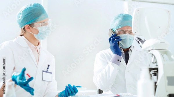Fototapeta scientists in a protective mask talking on a mobile phone.