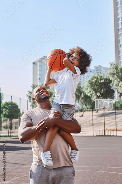 Fototapeta Happy dad holding kid on his shoulder during basketball