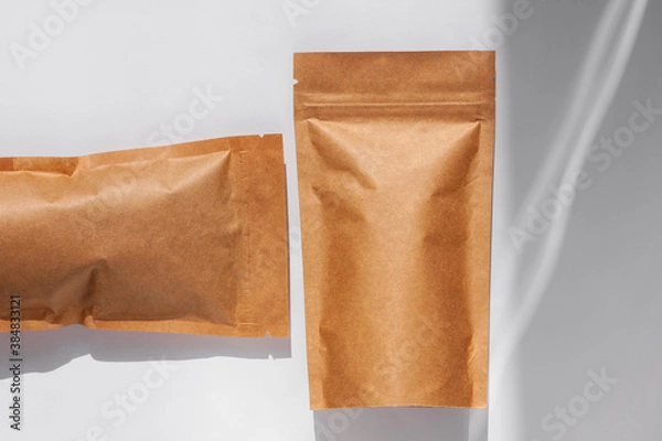 Fototapeta Brown kraft paper pouch bags with coffee beans top view with shadow isolated on white background. Packaging for foods and goods template mockup. Pack with clasp for tea leaves,weight products flat lay