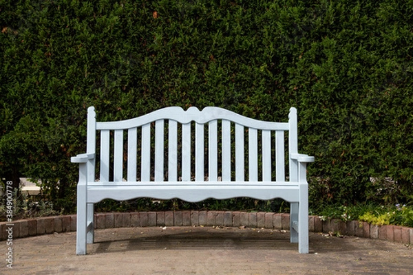 Fototapeta 緑の生垣の前に置かれた白いベンチ