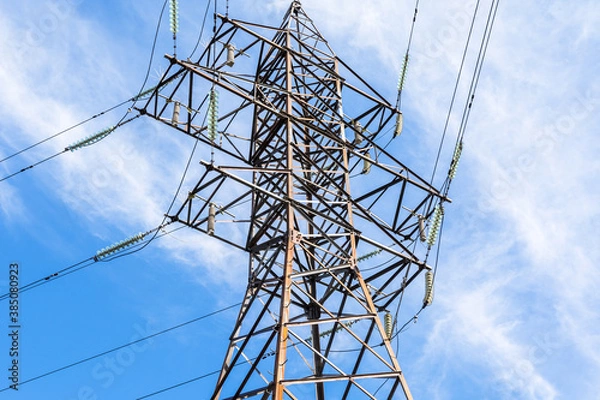 Obraz metal support of a high-voltage power line with wires and insulators against a blue sky with clouds