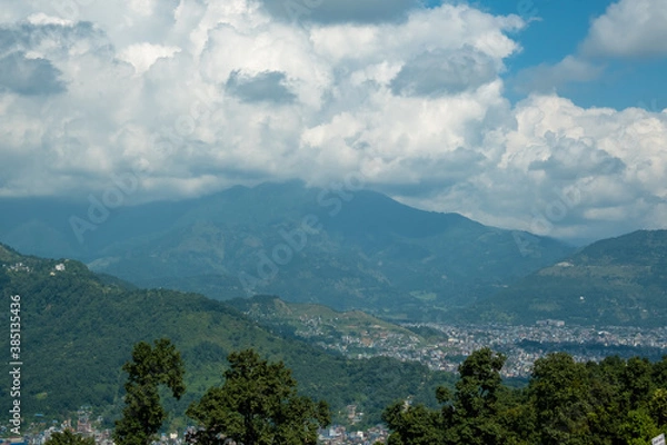 Fototapeta Aerial view of Pokhara city, Nepal, with surrounding hills and white cumulus clouds above them