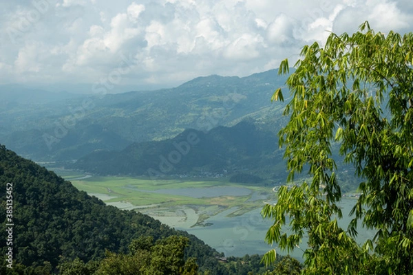 Fototapeta An aerial view of the hills near Pokhara, Nepal, and Lake Phewa, with white cumulus clouds above them