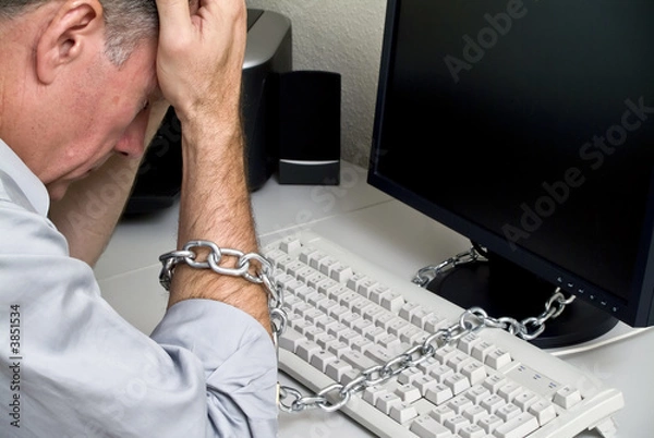 Obraz A man feeling as if he is chained to his computer 
