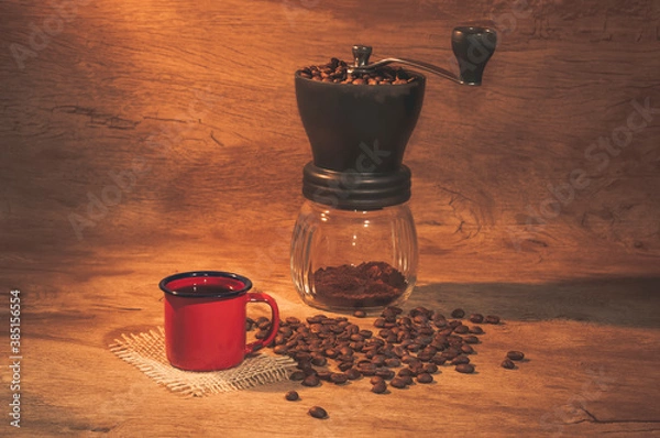 Obraz Red coffee mug with coffee grinder in the background. Rustic wooden background