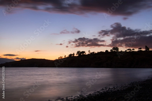 Fototapeta long exposure landscape that includes mountain silhouette, lake, clouds at the sundown