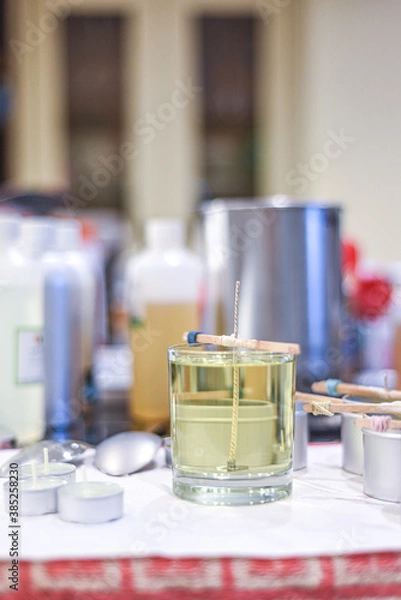 Fototapeta Making candles at home and adding a wick to liquid candle wax