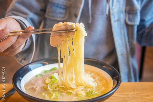 Obraz Hand pulling a ramen noodle with sliced of meat. Korean traditional soy milk noodle, Kong-GukSu