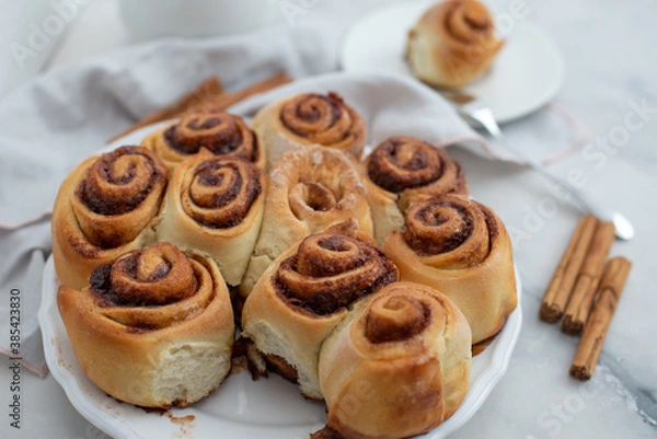 Fototapeta Cinnamon rolls with sugar frosting. With cinnamon sticks and spices, wooden background