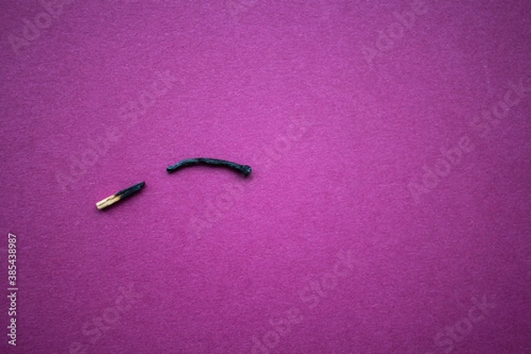 Fototapeta a burnt match broken in half on purple background