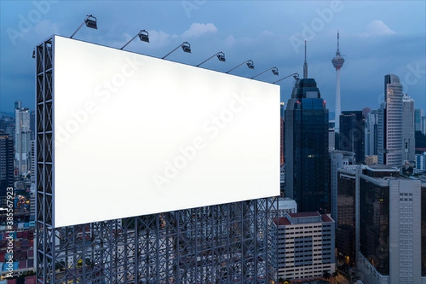Fototapeta Blank white road billboard with KL cityscape background at night time. Street advertising poster, mock up, 3D rendering. Side view. The concept of marketing communication to promote or sell idea.