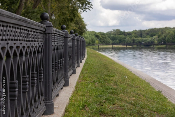 Fototapeta Railings of the embankment on the shore of the pond close up