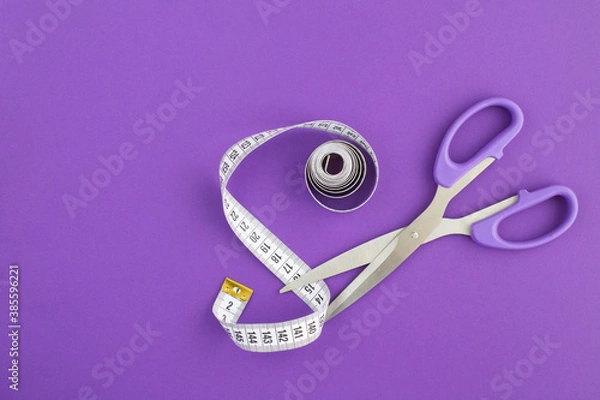 Fototapeta Closeup on white centimeter and scissors on the violet  background