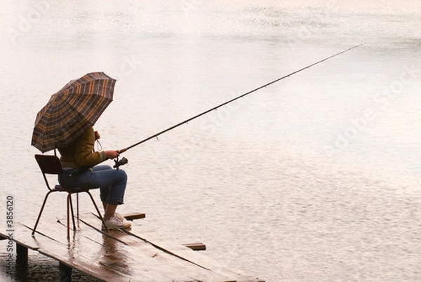 Obraz The woman fishes on lake under a rain
