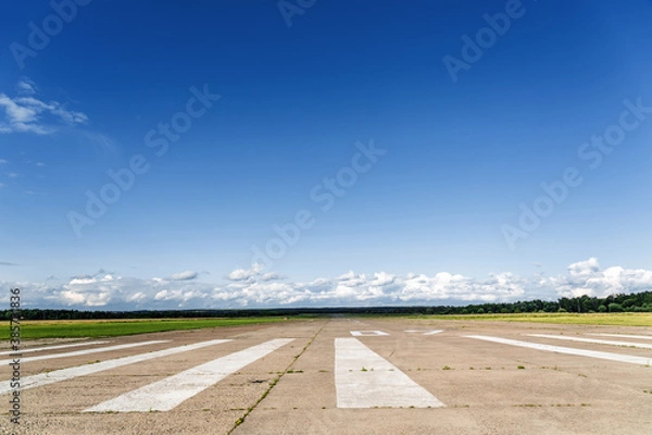 Obraz The runway of a rural small airfield against a blue sky with clouds of the airfield. Lonely airfield.