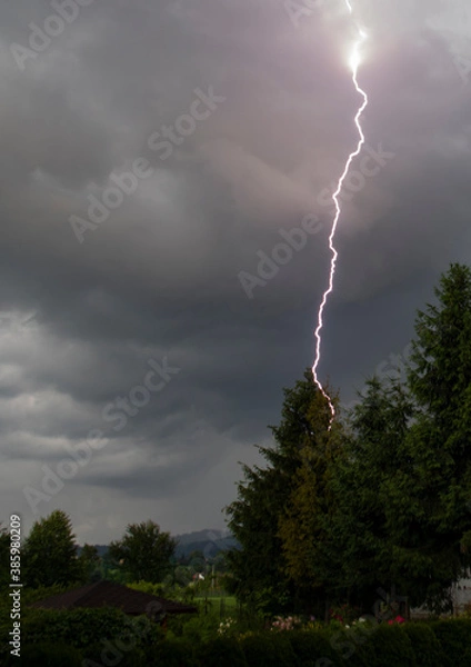 Fototapeta Thunderstorm with lightning and rain over the village