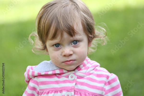 Obraz Close Up Portrait of a little 18 Month Old Girl with  Big Blue Eyes and Curly Hair, a girl Playing Outside, Funny Face Expression, Happy baby