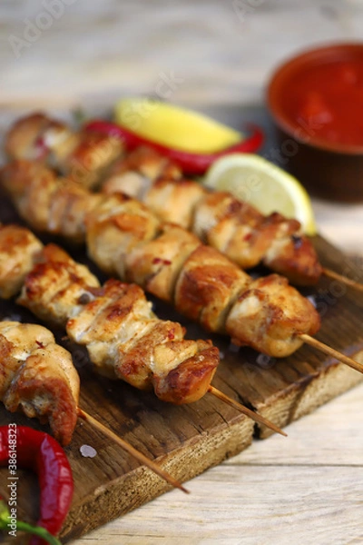 Fototapeta Selective focus. Appetizing chicken skewers on wooden sticks. Rustic style.