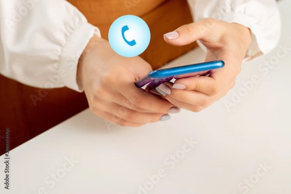 Fototapeta The girl dials a phone number on a smartphone, the icon with the phone, incoming and outgoing calls concept