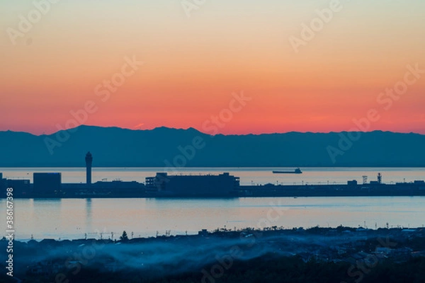 Obraz 樽水本宮神社から赤く焼けた綺麗な夕焼けと中部国際空港のシルエットを望む