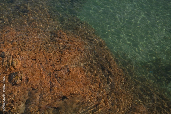 Fototapeta turquoise Mediterranean sea detail during summer with rocks, waves, and sunlight horizontal