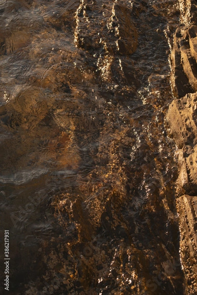 Fototapeta brown coastal rocks with limpets during sunset at the Mediterranean sea close-up vertical