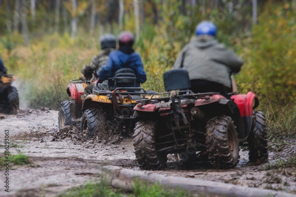 Fototapeta Group of riders riding atv vehicle on off road track, process of driving ATV vehicle, all terrain quad bike vehicle, during offroad competition, crossing a puddle of mud