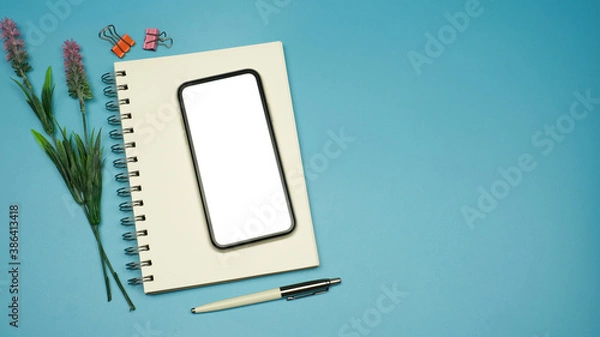 Fototapeta Flat lay, Workspace back to school and technology education concept on pink table desk with blank screen phone on blank notepad, green plant and stationery, Top view with copy space
