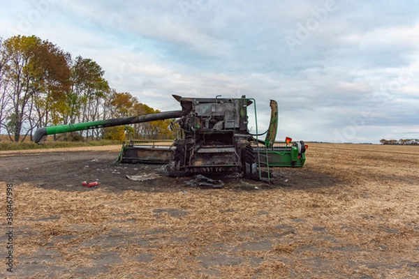 Fototapeta Aerial Back View of Burnt Combine Harvester on Grain Field in Rural North Dakota, taken at Daytime with Cloudy Sky.