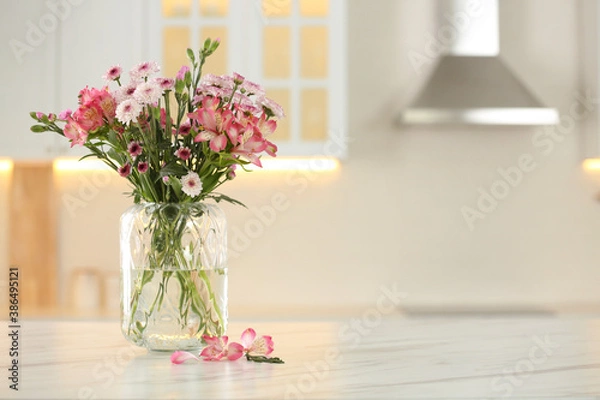 Fototapeta Vase with beautiful flowers on table in kitchen, space for text. Stylish element of interior design
