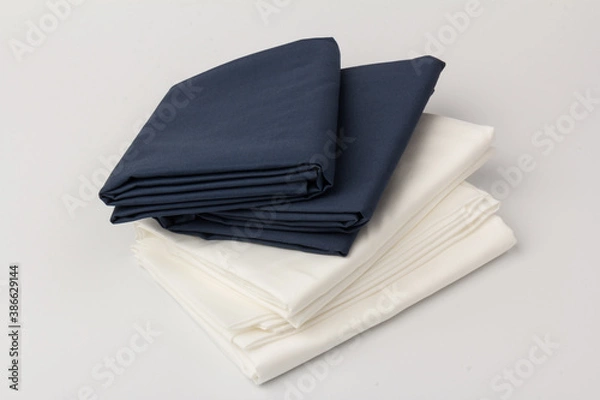 Fototapeta Stack of clean white and blue bed sheets on white  background, closeup.