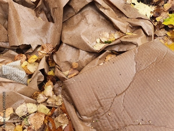 Fototapeta Crumpled wrapping paper and recycled cardboard boxes lie outside in the wet autumn foliage.