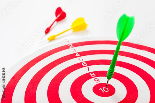 Fototapeta Close-up of a bull's eye on a wall with three Darts, one dart hits the target, the others lie side by side