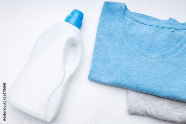 Fototapeta blank detergent bottle for laundry washing with coloured shirts on a white background. copy space. studio shot. above view