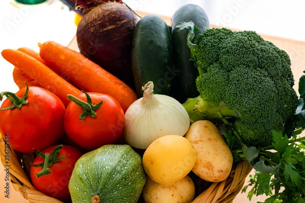 Fototapeta Tomato, green pumpkin, cucumber, beet, onion, potatoe and carrot in a tiny basket