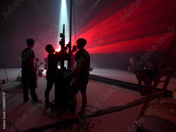 Obraz Blurry image and out of focus : Behind the scenes of video shooting production crew team silhouette and camera equipment in studio, Red laser light beam