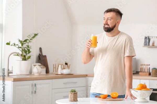 Fototapeta Man drinking orange juice at home