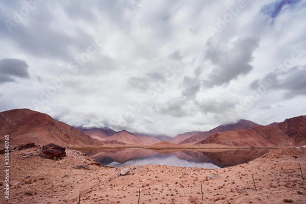 Obraz Lake surround by mountains with desert landscape and cloudy sky in Xinjian, China