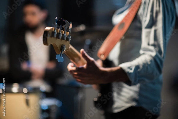 Fototapeta a member of a rock band at a jam session performs a musical part on bass guitar